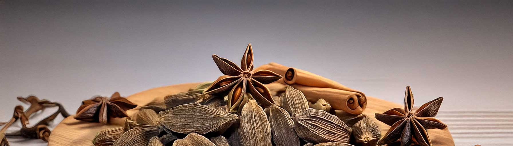 A detailed wide-angle view of black cardamom pods with cinnamon sticks, arranged on a clean, bright surface.