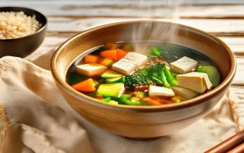 A vibrant macrobiotic meal with grains, vegetables, and a steaming bowl of miso soup on a rustic wooden table.