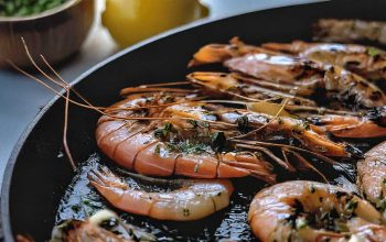 Shrimp sizzling in a pan with garlic and herbs.