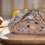 Loaf of walnut bread on a wooden cutting board with a knife